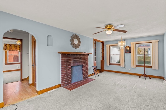 living area with baseboards, arched walkways, ceiling fan, carpet flooring, and a fireplace