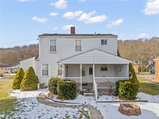 view of front of property with central air condition unit, a chimney, a fire pit, and a porch