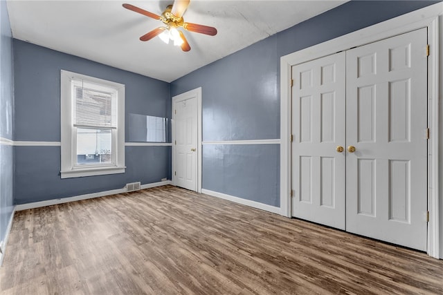 unfurnished bedroom featuring ceiling fan, wood finished floors, visible vents, and baseboards