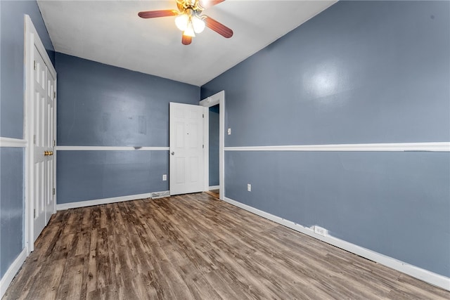 empty room featuring wood finished floors, a ceiling fan, and baseboards