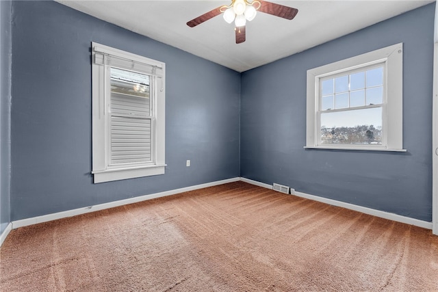 carpeted spare room with baseboards, visible vents, and ceiling fan