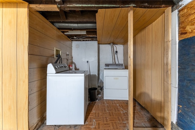 clothes washing area featuring laundry area, separate washer and dryer, and wood walls