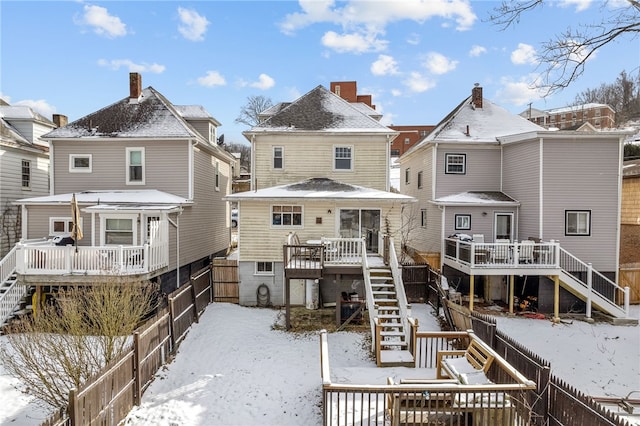 snow covered property with a deck, stairway, and a fenced backyard