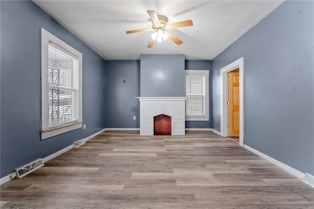 unfurnished living room with baseboards, visible vents, a ceiling fan, wood finished floors, and a fireplace