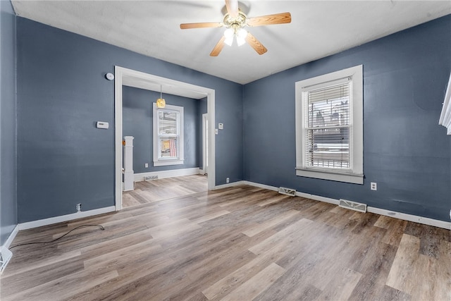 empty room with visible vents, ceiling fan, baseboards, and wood finished floors