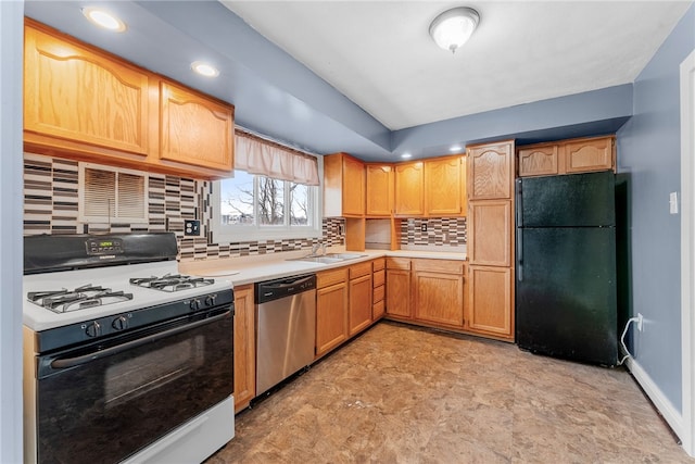 kitchen featuring tasteful backsplash, light countertops, stainless steel dishwasher, freestanding refrigerator, and gas range