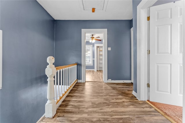 hall with attic access, baseboards, an upstairs landing, and wood finished floors