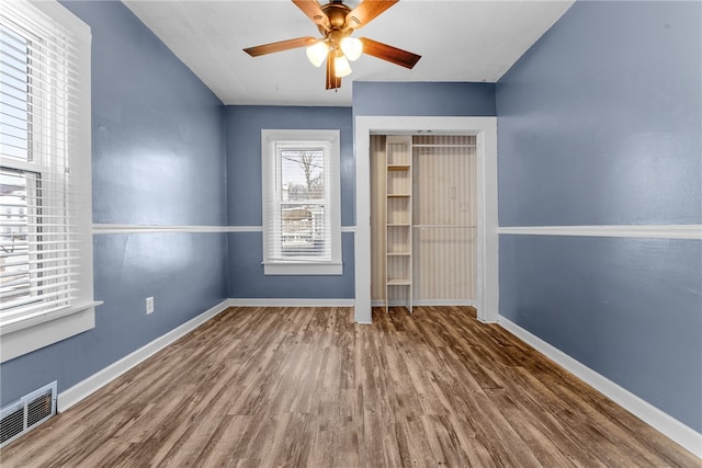 unfurnished bedroom with a closet, visible vents, baseboards, and wood finished floors