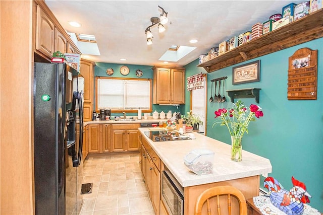 kitchen featuring a skylight, a sink, light countertops, a center island, and black appliances