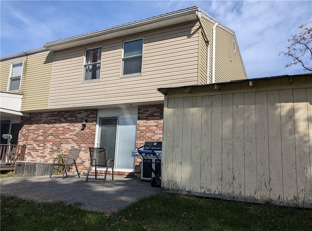 back of property with brick siding and a patio area