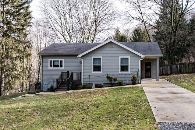 ranch-style house featuring a shingled roof, fence, and a front lawn