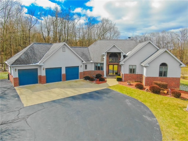 ranch-style home featuring brick siding, a front lawn, an attached garage, and aphalt driveway