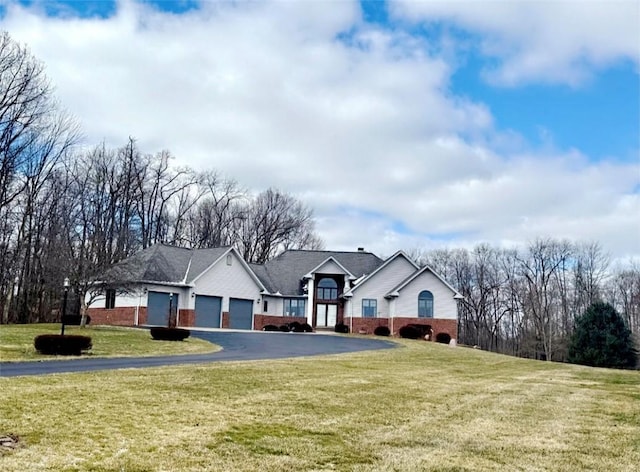 ranch-style house featuring a front lawn, brick siding, an attached garage, and aphalt driveway