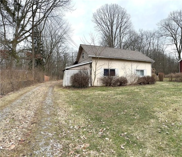 view of side of property with driveway and a lawn