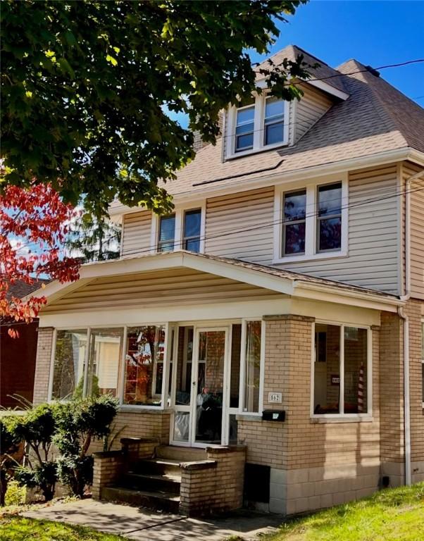 american foursquare style home with a shingled roof and brick siding