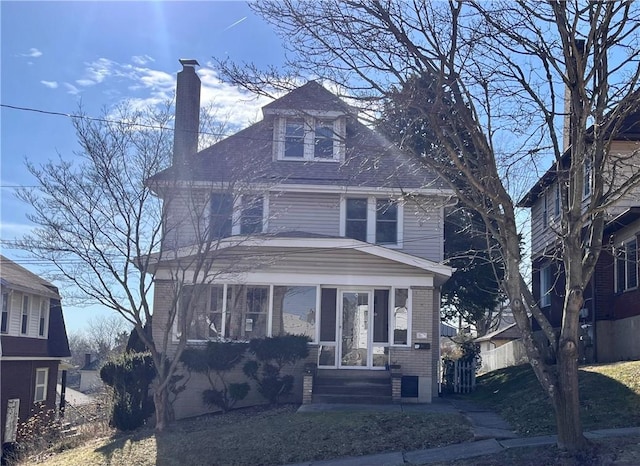 american foursquare style home featuring a chimney and brick siding