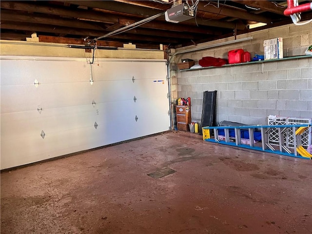 garage featuring concrete block wall and a garage door opener