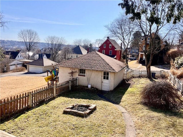 rear view of house with a yard, a residential view, a fire pit, and a fenced backyard