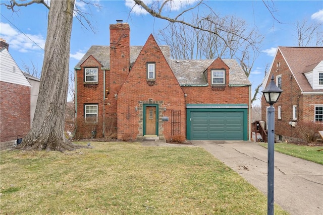 tudor house featuring a front yard, brick siding, driveway, and a chimney