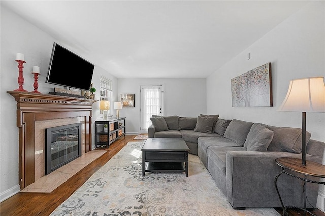 living room featuring wood finished floors, a glass covered fireplace, and baseboards