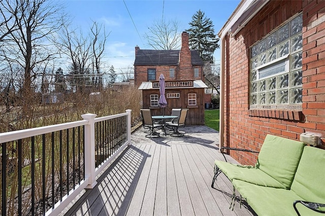 wooden deck with outdoor dining space and an outbuilding