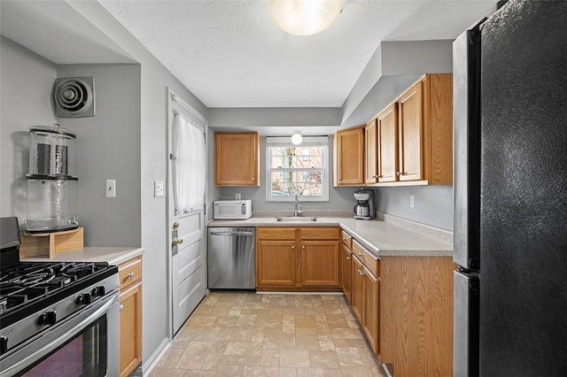 kitchen with light countertops, visible vents, appliances with stainless steel finishes, stone finish flooring, and a sink