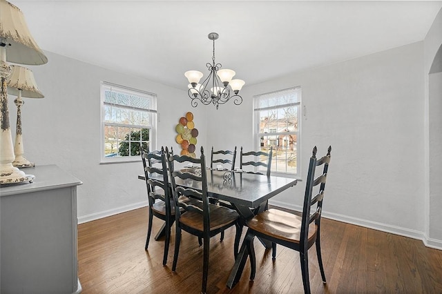 dining space with a notable chandelier, plenty of natural light, baseboards, and dark wood-type flooring