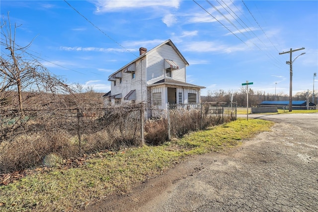 view of home's exterior featuring a chimney and fence