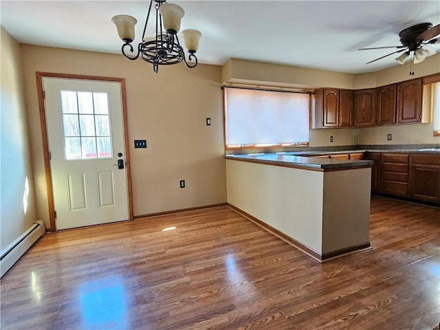 kitchen featuring dark countertops, a peninsula, baseboards, and wood finished floors