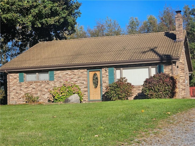 view of front of home with brick siding, a chimney, and a front yard