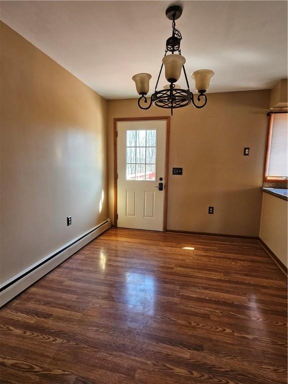 interior space with wood finished floors, baseboards, a chandelier, and a baseboard radiator