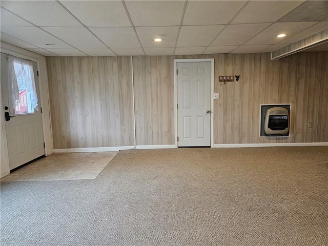 interior space with heating unit, a paneled ceiling, baseboards, and wood walls