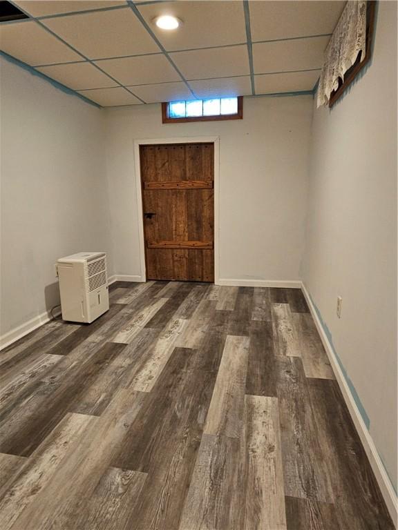 basement with a drop ceiling, baseboards, and wood finished floors