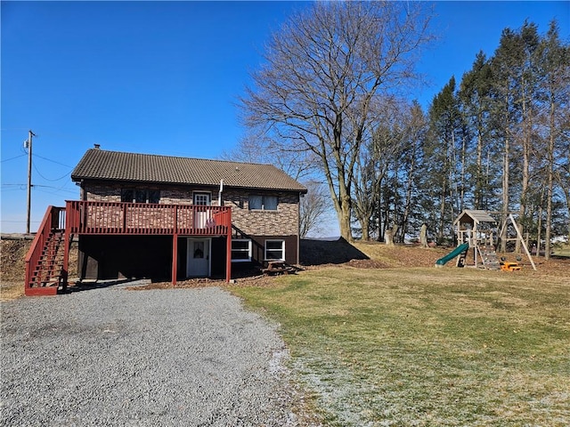 back of property featuring stairway, a lawn, a wooden deck, and a playground