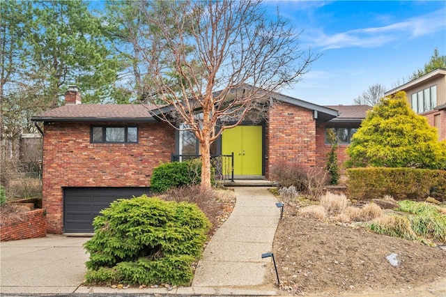 view of front facade featuring a garage, brick siding, driveway, and a chimney