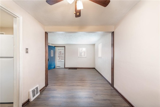 hallway with baseboards, a textured ceiling, visible vents, and wood finished floors