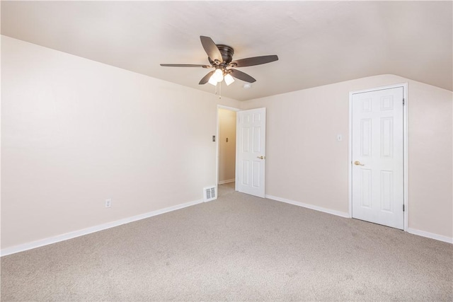 interior space featuring lofted ceiling, light colored carpet, visible vents, a ceiling fan, and baseboards