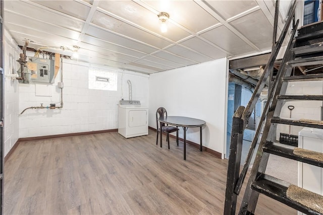 basement with concrete block wall, washer / dryer, electric panel, baseboards, and wood finished floors