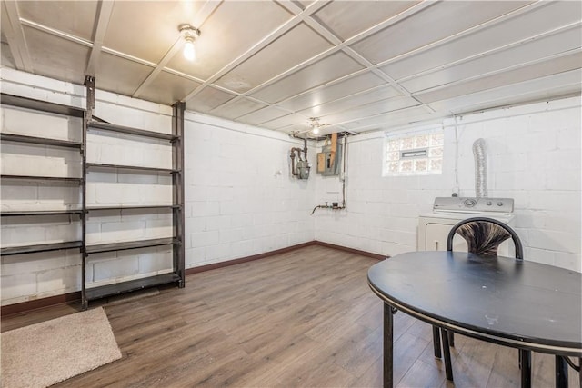 basement with concrete block wall, washer / clothes dryer, and wood finished floors