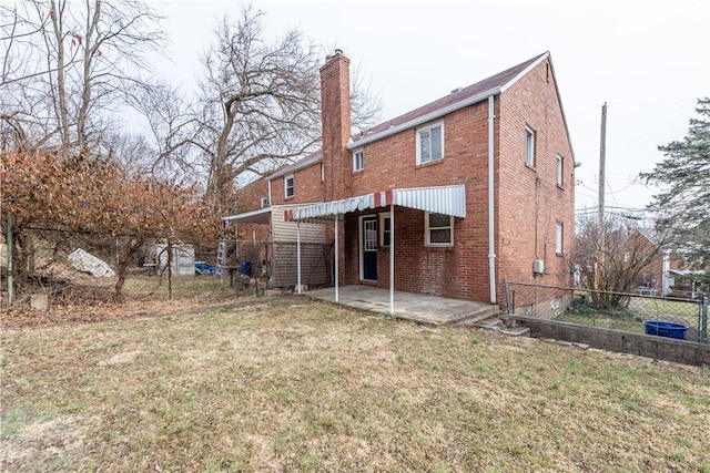 rear view of house with a yard, brick siding, a chimney, and fence