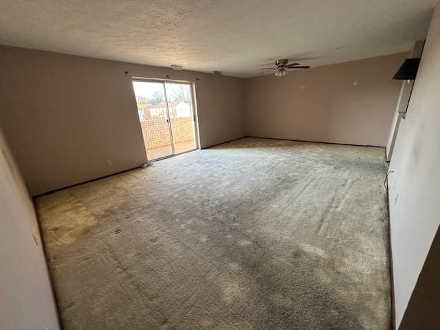 empty room featuring light carpet, a ceiling fan, and a textured ceiling