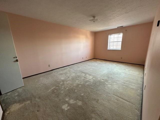 empty room with a textured ceiling and carpet flooring