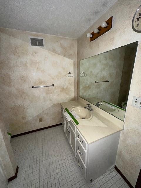 bathroom featuring baseboards, visible vents, vanity, and a textured ceiling