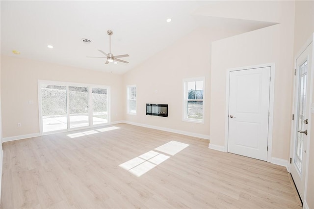 unfurnished living room featuring visible vents, a glass covered fireplace, ceiling fan, light wood-style floors, and high vaulted ceiling