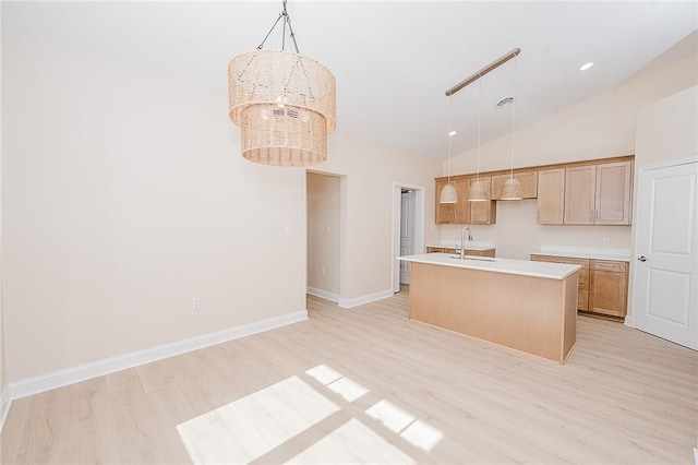 kitchen with baseboards, an island with sink, light wood-style flooring, hanging light fixtures, and light countertops