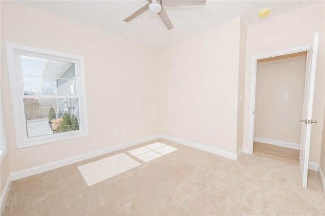 spare room featuring light carpet, ceiling fan, and baseboards