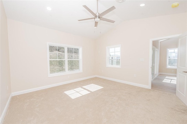 empty room featuring plenty of natural light, light carpet, vaulted ceiling, and baseboards