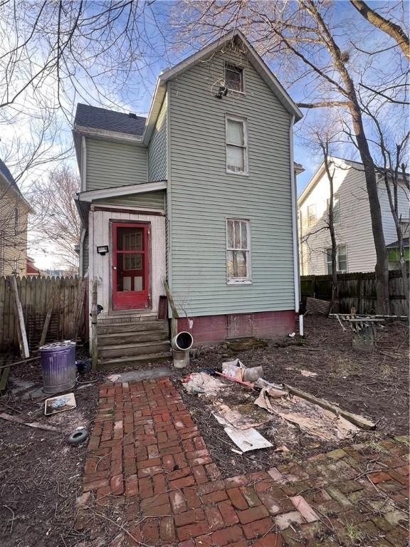 rear view of property featuring entry steps and fence