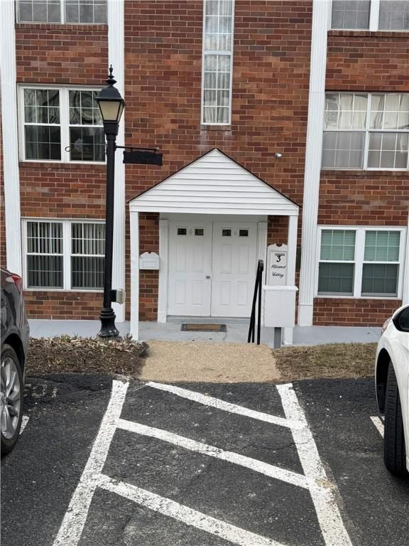 doorway to property with uncovered parking and brick siding