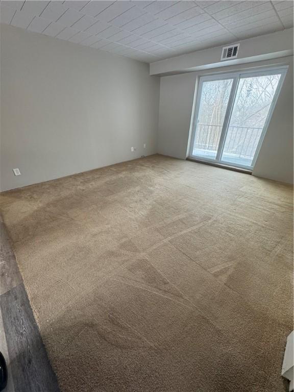 empty room featuring carpet floors and visible vents